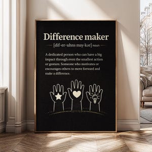 May include: A framed print with the words "Difference maker" in white on a black background. The definition is provided below the title. Three white hand illustrations with a star, heart, and lightbulb are at the bottom.