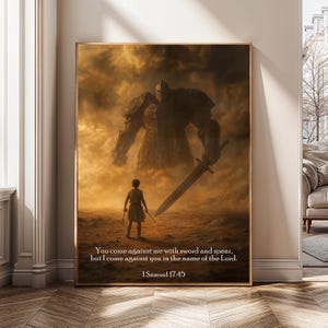 May include: Framed artwork depicting a dramatic scene with a giant figure and a smaller figure facing each other. The artwork is in shades of brown and gold, with text from 1 Samuel 17:45. The artwork is displayed in a room with a wooden floor.
