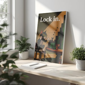 May include: A framed cartoon print featuring Tom from Tom and Jerry wearing sunglasses and using a vintage phone. The print has the words "Lock in." at the top. The print is on a desk with a notebook, pen, and potted plants.