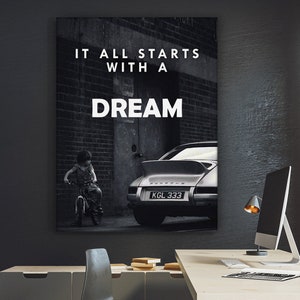 May include: Black and white photo of a child on a bicycle in front of a brick wall with a vintage car parked in the background. The text "It all starts with a dream" is printed on the wall.