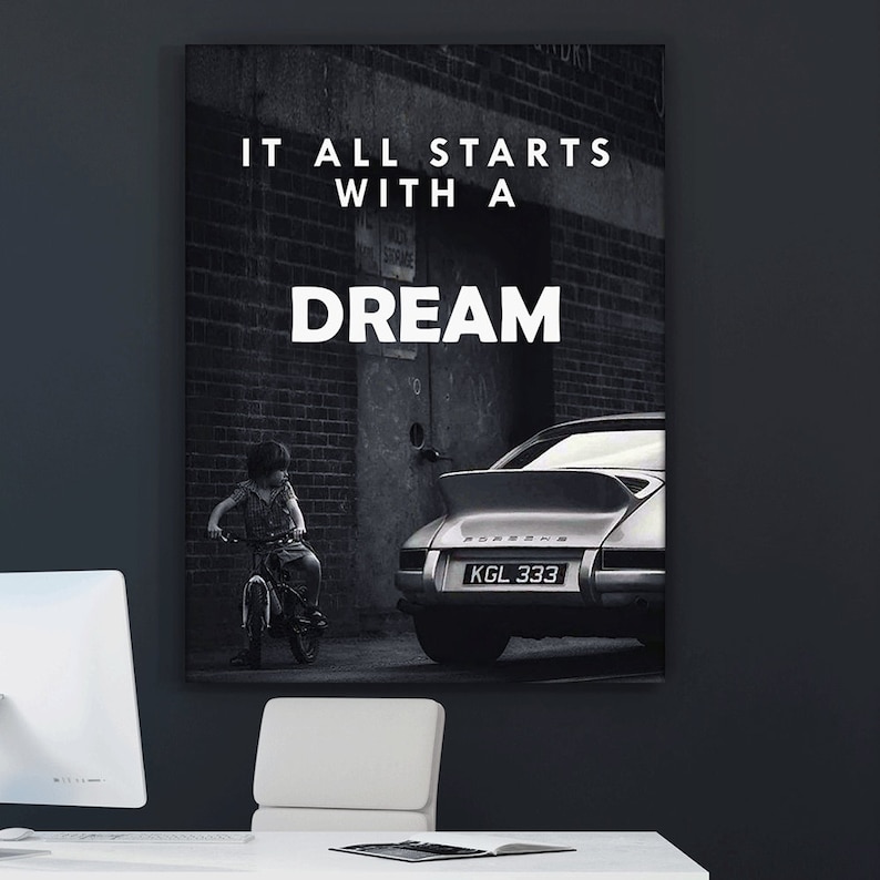 May include: Black and white photo of a child riding a bicycle in front of a brick building with a classic silver Porsche parked in the background. The text "IT ALL STARTS WITH A DREAM" is printed on the wall.