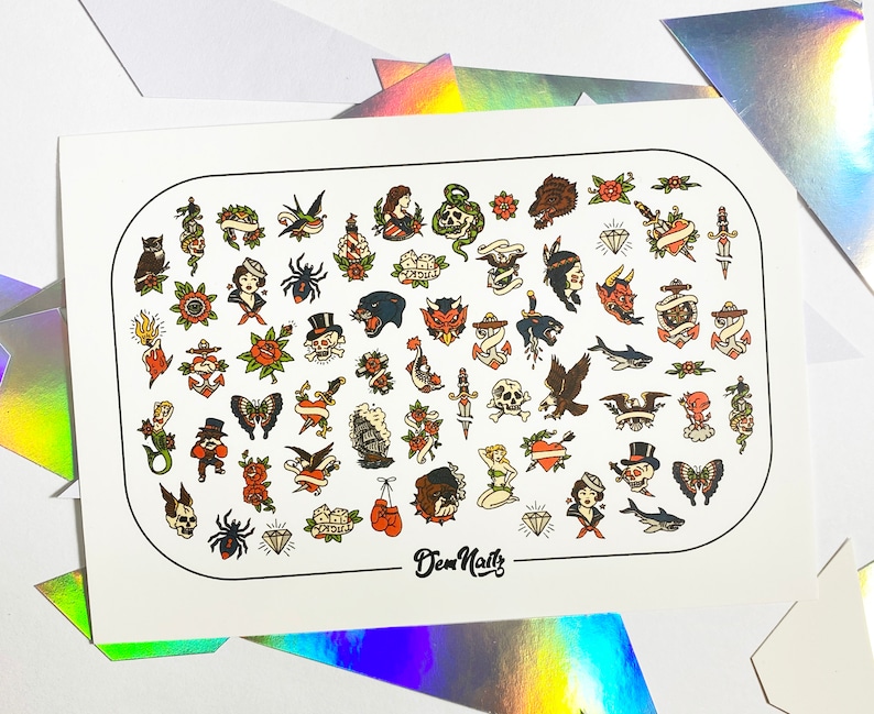 May include: A sheet of white paper with a variety of colorful tattoo-style nail decals. The decals feature images of skulls, hearts, anchors, butterflies, and other traditional tattoo designs. The sheet is labeled "Dew Nails".