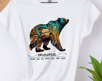May include: White t-shirt with a colorful floral bear design and the word "mama" underneath. The text below the bear says "inspiring, brave, kind, beautiful, dares,  chases,  creates,  amazing."