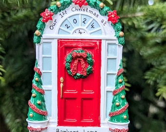 Peut inclure: Une décoration de Noël rouge et blanche en forme de maison avec une porte rouge, une couronne et deux petits sapins de Noël. L'ornement dit "Our 1st Christmas at 2024 Barkers Lane".
