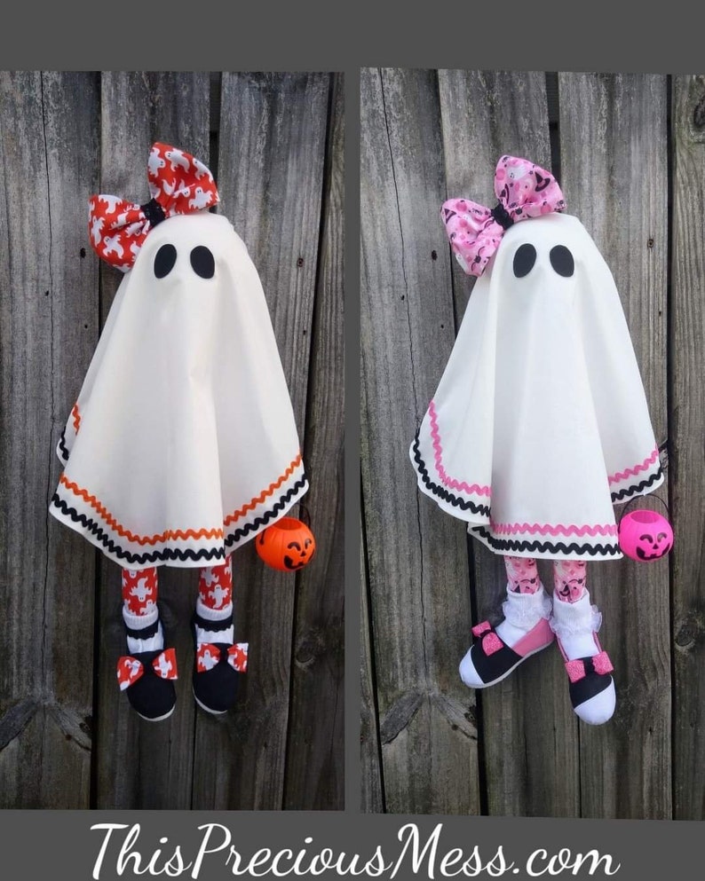 Op de afbeelding: Twee witte spookpoppen met zwarte ogen en zwart-wit gestreepte benen. E&eacute;n spookpop heeft een rode strik met een wit en oranje patroon en oranje-zwart gestreepte rand. De andere spookpop heeft een roze strik met een wit en roze patroon en roze-zwart gestreepte rand. Beide poppen houden oranje pompoen-emmers vast.