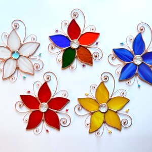 Peut inclure: Cinq attrape-soleil en verre color&eacute; en forme de fleurs avec des accents de fil de cuivre. Les fleurs sont rouges, blanches, bleues, jaunes et vertes. Chaque fleur a un centre en verre transparent.