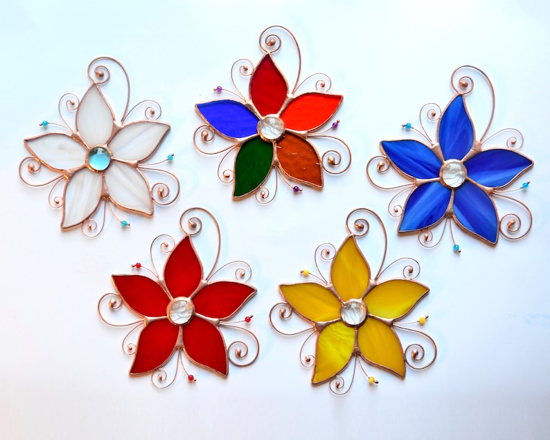 Peut inclure: Cinq attrape-soleil en verre color&eacute; en forme de fleurs avec des accents de fil de cuivre. Les fleurs sont rouges, blanches, bleues, jaunes et vertes. Chaque fleur a un centre en verre transparent.