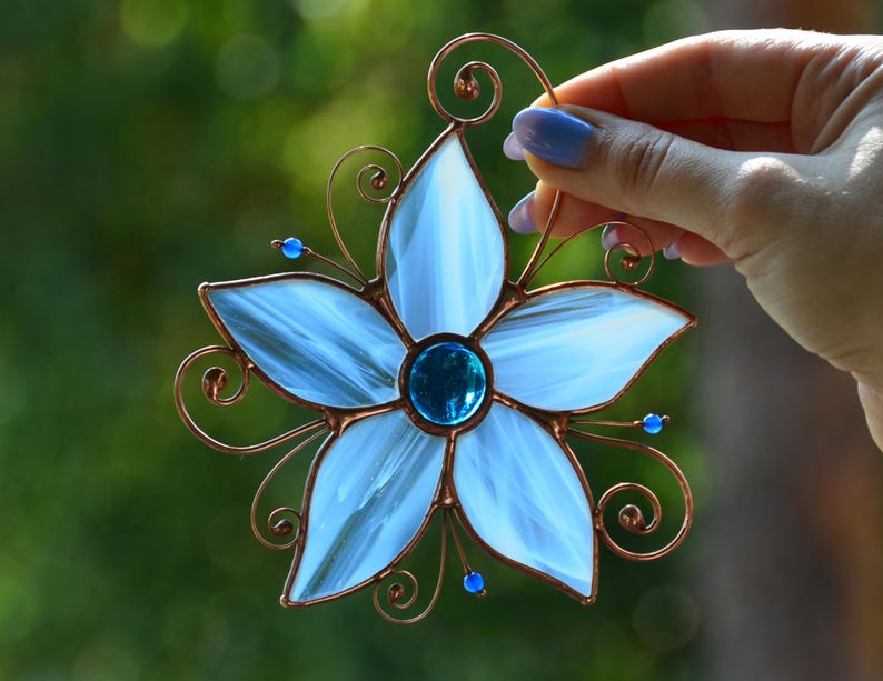 Peut inclure: Une fleur en verre teint&eacute; bleu avec un cadre en fil de cuivre et des perles de verre bleues. La fleur a cinq p&eacute;tales et un centre en verre bleu.