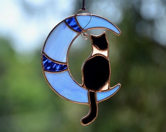 Gato de vidrieras en la ventana de la luna colgando