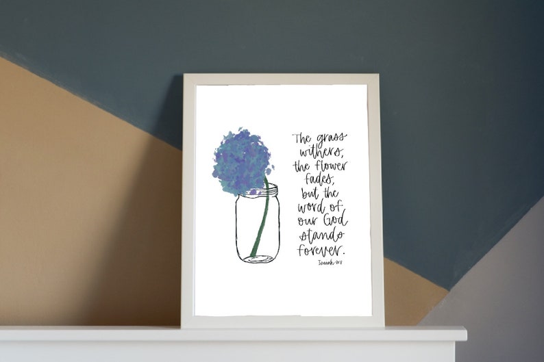 May include: A white framed print with a blue watercolor flower in a mason jar. The print features a bible verse: "The grass withers, the flower fades, but the word of our God stands forever."  - Isaiah 40:8