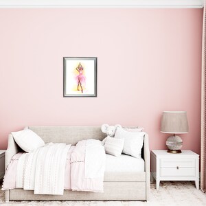 May include: A framed watercolor painting of a ballerina in a pink tutu, arms raised, set against a yellow and pink background. The artwork hangs on a pink wall above a bed with white and pink bedding.
