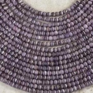 以下が含まれることがあります： 紫と白のストライプ模様の宝石ビーズの糸。ビーズは丸く、滑らかで磨かれた仕上げになっています。
