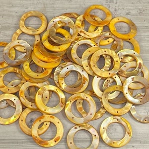 May include: A pile of round, iridescent, mother-of-pearl shell beads in shades of gold and brown. The beads have a smooth, polished finish and are perfect for jewelry making.