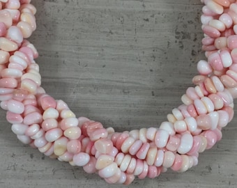 Op de afbeelding: Een streng roze en witte schelp kralen, met een gladde, afgeronde vorm. De kralen zijn aan elkaar geregen om een ​​ketting of armband te maken.