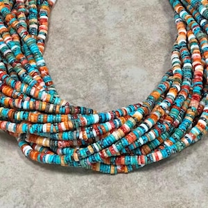 Peut inclure: Gros plan sur un collier à plusieurs rangs avec de petites perles plates. Les perles sont un mélange de turquoise, d'orange, de blanc et de rouge. Le collier a un design superposé, avec plusieurs rangs en cascade. Le thème général est celui des bijoux bohèmes.