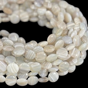 May include: A strand of white agate beads with a striped pattern. The beads are oval shaped and have a smooth, polished finish.