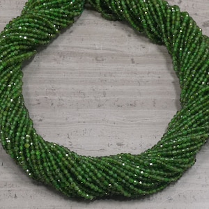 May include: A strand of green gemstone beads, likely peridot, with a faceted finish. The beads are small and uniform in size, creating a smooth and elegant look.