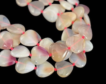May include: A strand of heart-shaped agate beads with pink and white stripes. The beads are strung on a red cord.