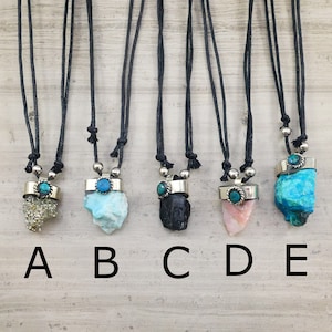 May include: Five necklaces with different crystal pendants. Each necklace features a turquoise stone and a silver setting. The crystals are pyrite, aquamarine, black tourmaline, rose quartz, and turquoise.