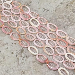 May include: A strand of pink and white oval shell beads with a hole in the centre of each bead. The beads are arranged in rows and are strung on a white cord.