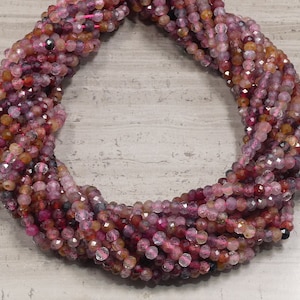 Peut inclure: Un brin de perles de pierres précieuses facettées roses, rouges et brunes. Les perles mesurent environ 4 mm et ont une forme légèrement irrégulière.