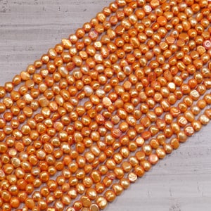 Peut inclure: Un brin de perles d'eau douce de couleur orange. Les perles sont de forme irrégulière et ont une finition légèrement irisée.