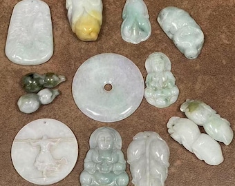 Puede incluir: Una colección de 11 colgantes de jade de diferentes formas y tamaños, incluyendo un colgante redondo con un agujero en el centro, un colgante con forma de hoja y un colgante con una figura de una persona. Los colgantes están todos tallados en jade verde y tienen un acabado liso y pulido.