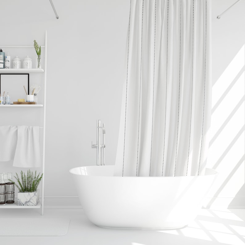 May include: White bathtub with a white shower curtain with black vertical stripes. The shower curtain is partially pulled back to reveal the bathtub. The bathtub is in a white bathroom with a white shelf unit in the background.