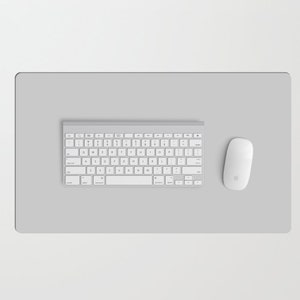 May include: A white wireless keyboard and mouse on a gray desk mat. The keyboard has a standard layout with function keys and a numeric keypad. The mouse has a simple design with a single button and a scroll wheel.