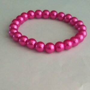 May include: A pink pearl bracelet with a shiny finish.