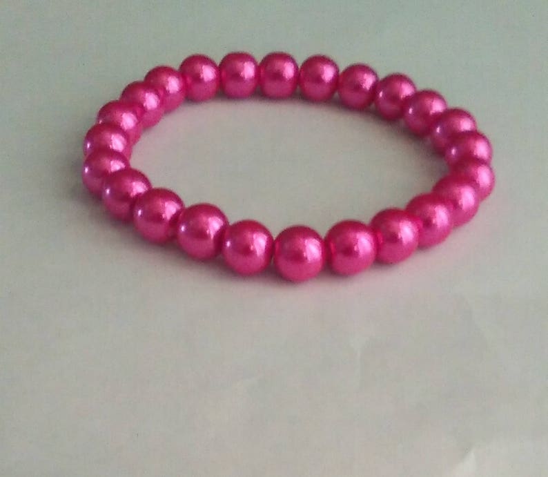 May include: A pink pearl bracelet with a shiny finish.