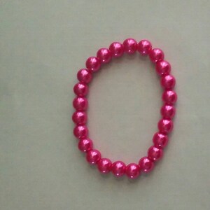 May include: A pink pearl bracelet with a simple design.