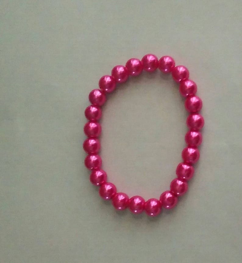 May include: A pink pearl bracelet with a simple design.