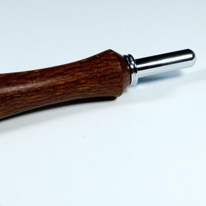 May include: A wooden tool with a brown handle and a silver metal tip. The tool is used for punching holes in leather or fabric.