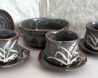 Juego de tazas de té de cerámica artística, hechas y pintadas a mano al estilo japonés. Esmaltado en gris con efecto goteo sobre fondo rojo con hierbas/juncos blancos.