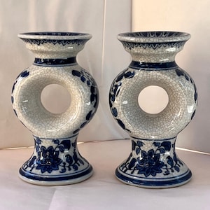 Puede incluir: Dos jarrones de cerámica azul y blanca con un diseño único en forma de rosquilla. Los jarrones presentan un esmalte craquelado, motivos florales y una base acampanada. El diseño es de estilo clásico y elegante.