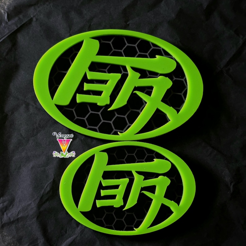 May include: Two oval-shaped lime green emblems featuring a cutout Japanese kanji character inside a black hexagonal honeycomb grid. The emblems are framed by a solid lime green border. A small logo with the text Vongsai is visible on the left.