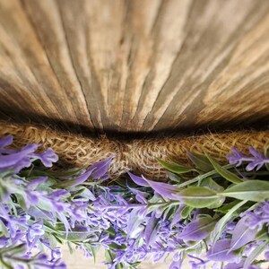 May include: A purple lavender wreath with burlap backing. The wreath is hanging on a wooden surface.
