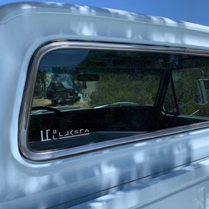 May include: A blue pickup truck with a white sticker on the back window that says "LL'J<=>A".