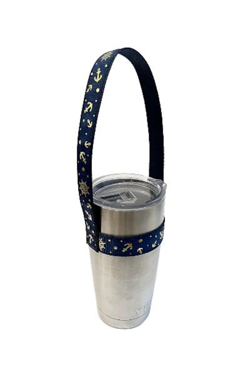 Op de afbeelding: Een roestvrijstalen tumbler met een marineblauwe en gouden anker-themaband. De band heeft een lus om de tumbler te dragen.