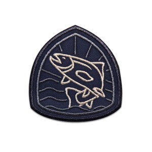 May include: A navy blue embroidered patch with a white outline of a fish jumping out of the water. The patch has a sunburst design behind the fish.