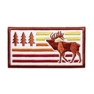May include: An embroidered patch with a red and brown elk standing in front of a sunset-colored American flag with three pine trees on the left side.