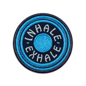 May include: A blue and black embroidered patch with the words "INHALE EXHALE" in white.