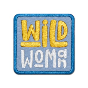 May include: A blue and white embroidered patch with the text "WILD WOMAN" in yellow and white lettering.