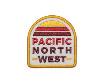 May include: A white embroidered patch with a yellow outline. The patch features a stylized sunset with red, orange, and brown stripes. The text "PACIFIC NORTH WEST" is written in brown letters below the sunset.
