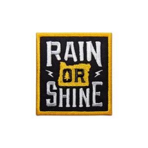 May include: A black and yellow embroidered patch with the text "RAIN OR SHINE" and a stylized outline of the state of Oregon with a pine tree inside.