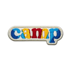 Pode incluir: Um remendo branco bordado com a palavra "camp" em letras coloridas. As letras s&atilde;o contornadas em branco e est&atilde;o em um esquema de cores arco-&iacute;ris: azul, amarelo, vermelho, amarelo, azul.