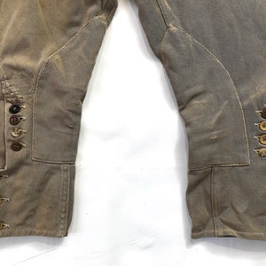 May include: A pair of brown riding breeches with button detailing on the legs. The breeches are made of a thick, durable fabric and have a classic equestrian style.
