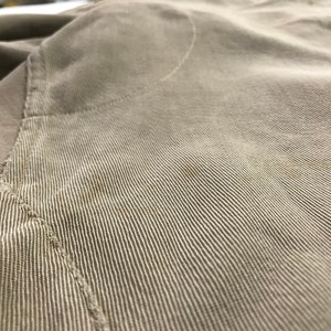 May include: Close-up of a light brown corduroy fabric with a subtle texture and a single seam running diagonally across the image.
