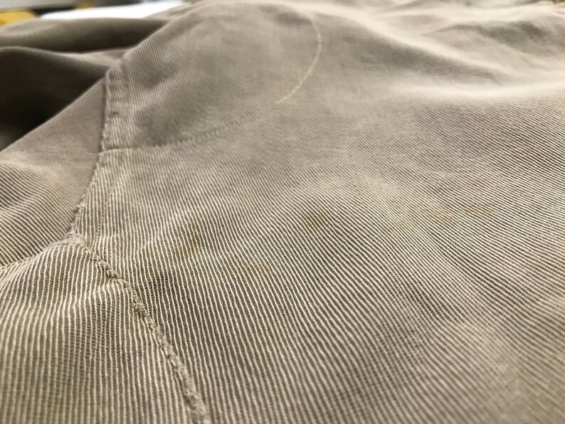 May include: Close-up of a light brown corduroy fabric with a subtle texture and a single seam running diagonally across the image.